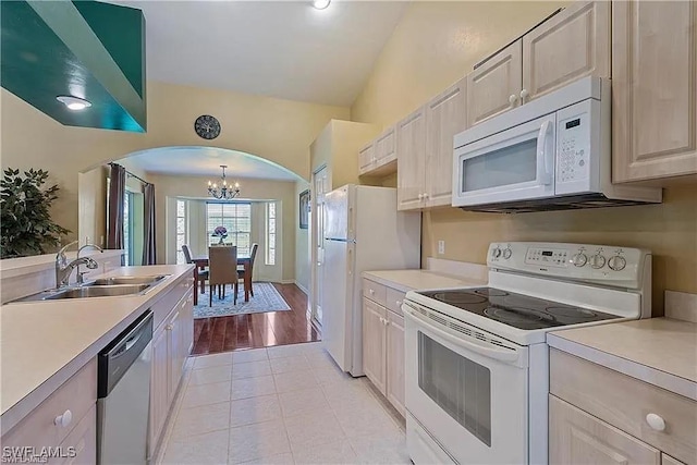 kitchen with sink, hanging light fixtures, light tile patterned floors, a notable chandelier, and white appliances