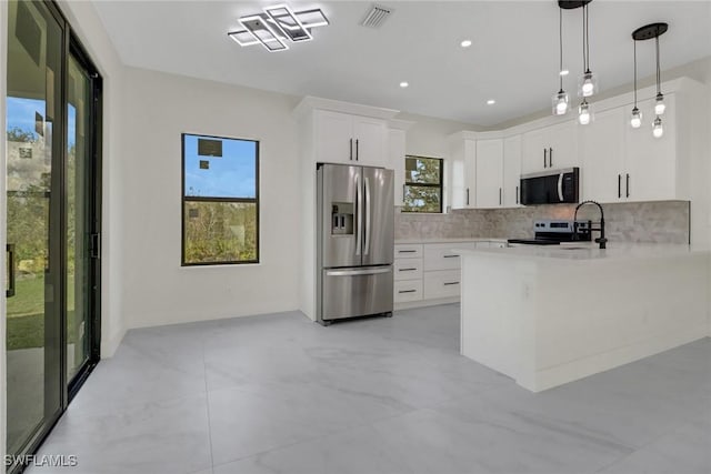 kitchen featuring pendant lighting, decorative backsplash, white cabinets, and appliances with stainless steel finishes