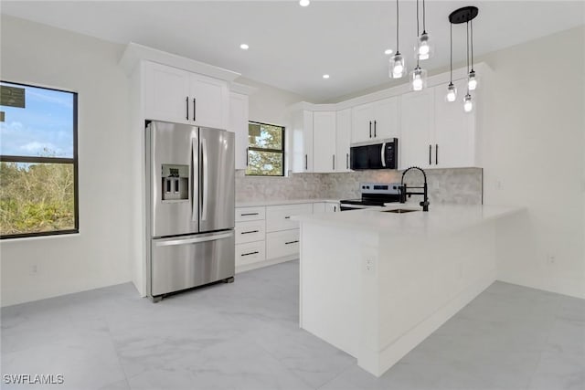 kitchen featuring stainless steel appliances, hanging light fixtures, sink, and white cabinets