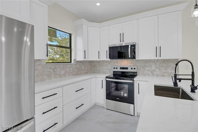 kitchen with appliances with stainless steel finishes, pendant lighting, white cabinetry, sink, and backsplash