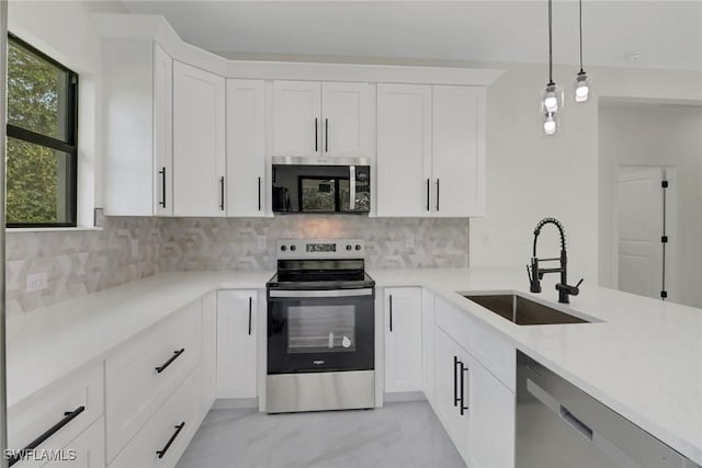 kitchen featuring appliances with stainless steel finishes, sink, pendant lighting, and white cabinets