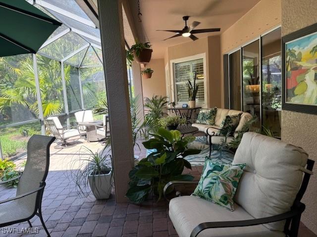 view of patio / terrace with ceiling fan, an outdoor hangout area, and glass enclosure