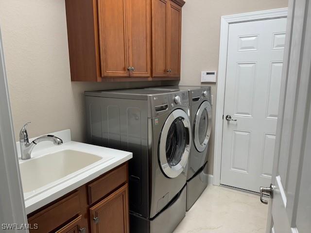 washroom with cabinets, washer and clothes dryer, and sink