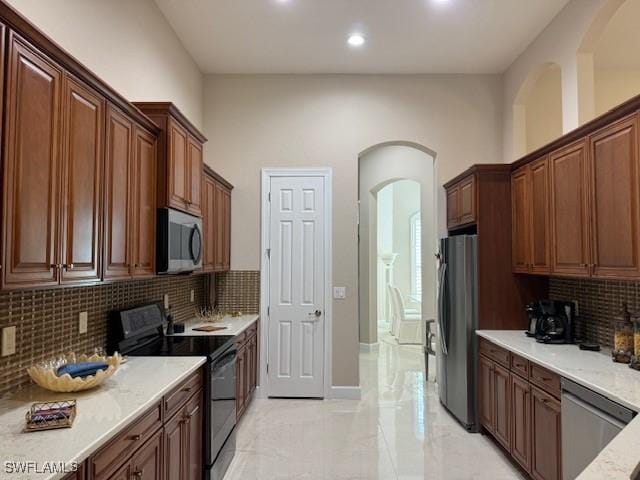 kitchen with light stone counters, stainless steel appliances, and decorative backsplash