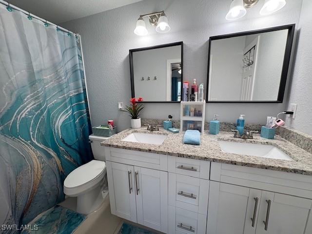 bathroom with a textured wall, a sink, and double vanity