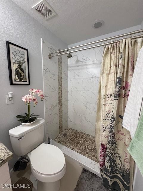 bathroom featuring toilet, a stall shower, vanity, and visible vents