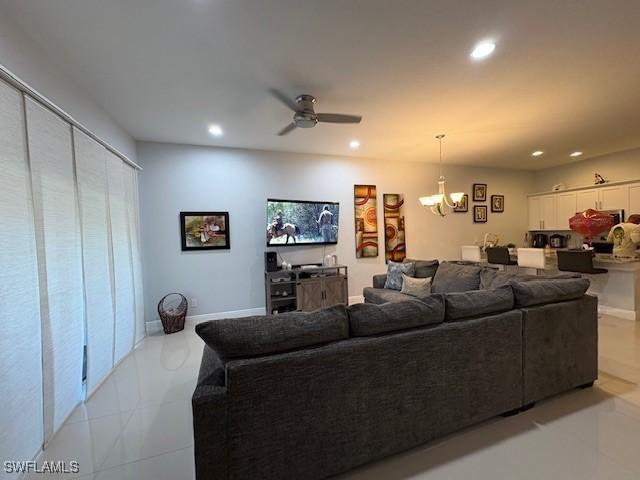 living area with recessed lighting, baseboards, and ceiling fan with notable chandelier