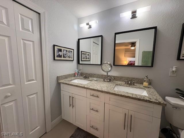 full bathroom featuring a sink, double vanity, toilet, and a closet