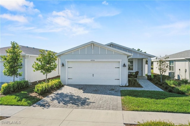 single story home with central AC, a garage, and a front lawn