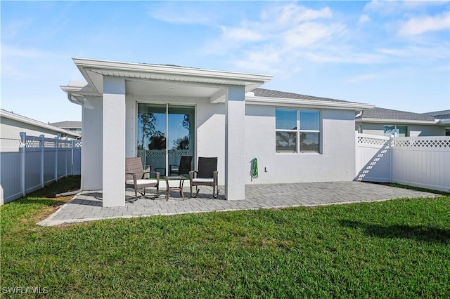 rear view of property featuring a patio area and a lawn