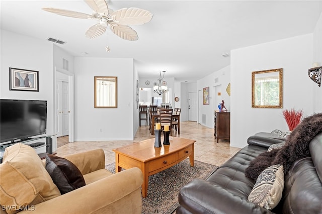 living area featuring ceiling fan with notable chandelier, light tile patterned floors, visible vents, and baseboards