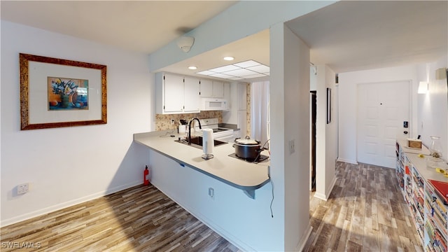 kitchen with sink, white appliances, white cabinets, and hardwood / wood-style flooring