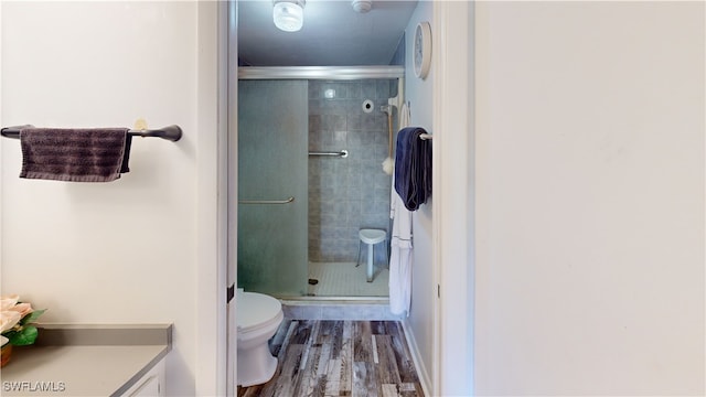 bathroom featuring hardwood / wood-style flooring, a shower with shower door, and toilet