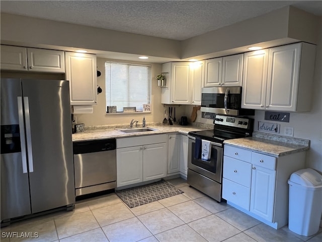 kitchen with sink, a textured ceiling, stainless steel appliances, and white cabinets