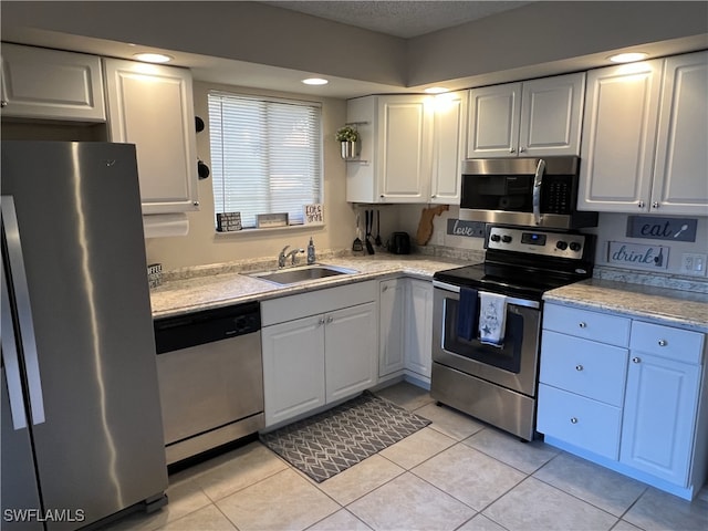 kitchen featuring sink, white cabinets, light tile patterned floors, stainless steel appliances, and a textured ceiling