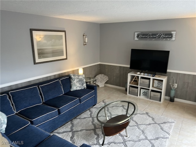 living room featuring tile patterned floors, wooden walls, and a textured ceiling