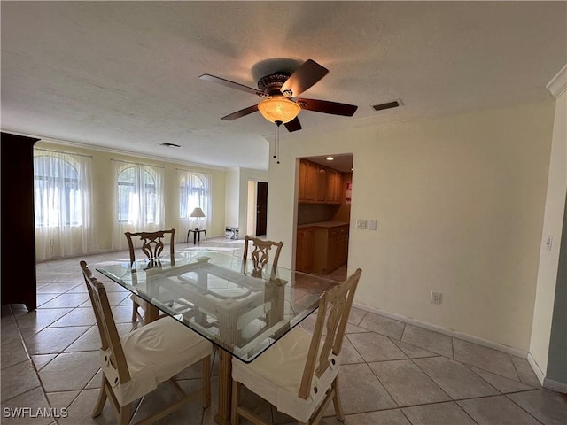 unfurnished dining area featuring light tile patterned flooring, ceiling fan, ornamental molding, and a textured ceiling