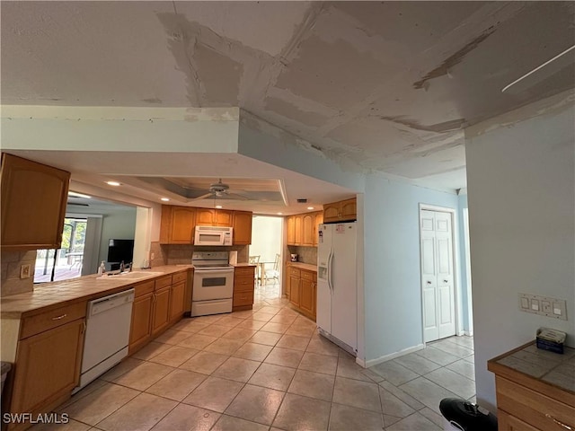 kitchen with sink, white appliances, light tile patterned floors, tasteful backsplash, and a raised ceiling