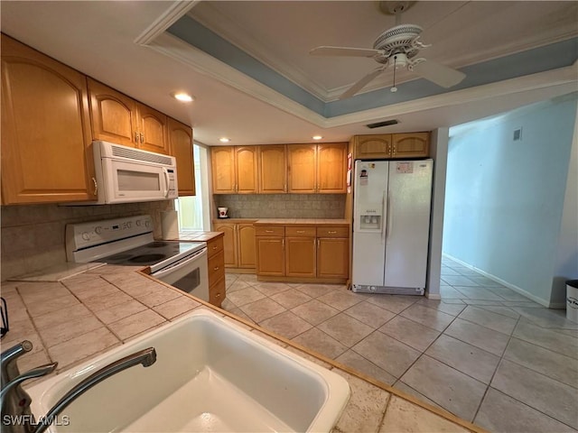 kitchen with tasteful backsplash, ornamental molding, white appliances, and a tray ceiling