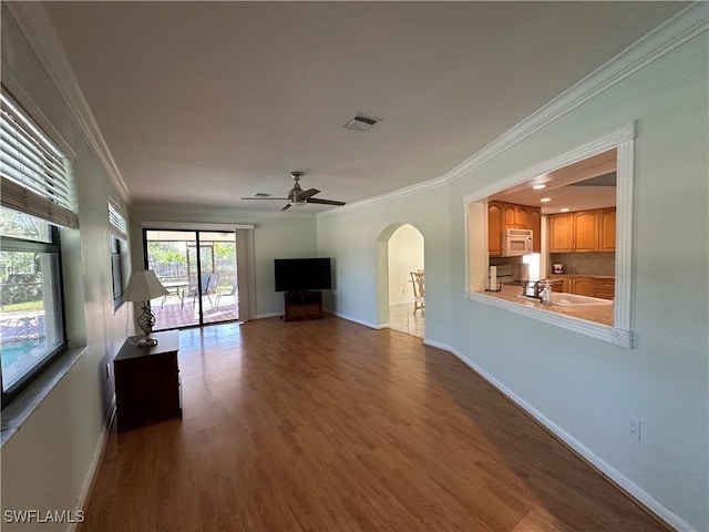 unfurnished living room featuring hardwood / wood-style flooring, ceiling fan, crown molding, and sink