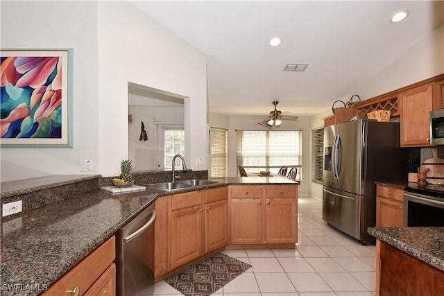 kitchen with sink, light tile patterned floors, appliances with stainless steel finishes, kitchen peninsula, and dark stone counters