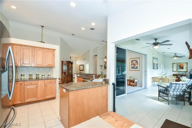 kitchen with tasteful backsplash, lofted ceiling, sink, stainless steel fridge, and light tile patterned floors