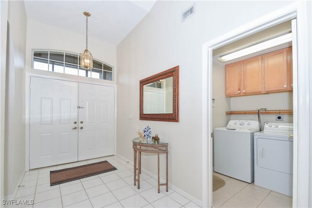 tiled entrance foyer featuring washing machine and dryer and a chandelier