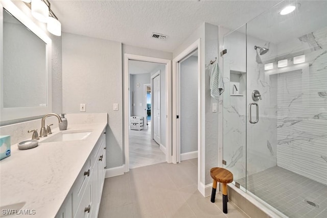 bathroom featuring vanity, a textured ceiling, and a shower with shower door