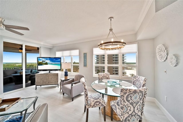 dining space featuring ceiling fan with notable chandelier, ornamental molding, and a textured ceiling