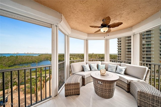 sunroom / solarium featuring a water view, ceiling fan, and a wealth of natural light