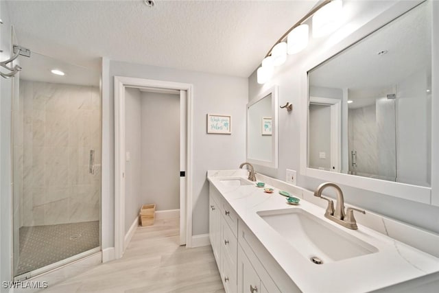 bathroom featuring a shower with door, vanity, and a textured ceiling