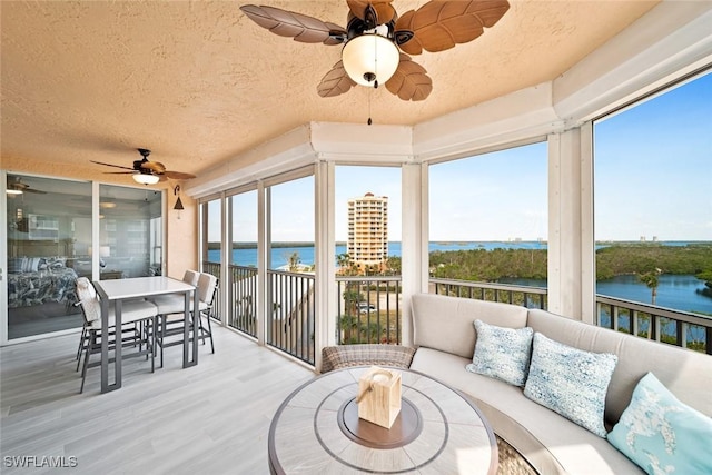 sunroom with a water view and ceiling fan