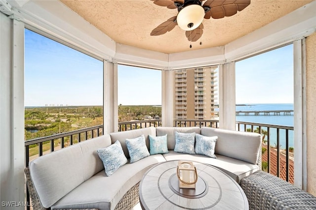 sunroom / solarium with ceiling fan and a water view