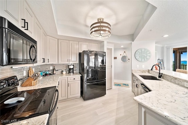 kitchen with tasteful backsplash, light stone countertops, sink, and black appliances