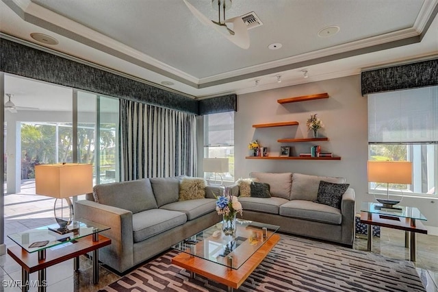 living area featuring a tray ceiling, a healthy amount of sunlight, visible vents, and ornamental molding