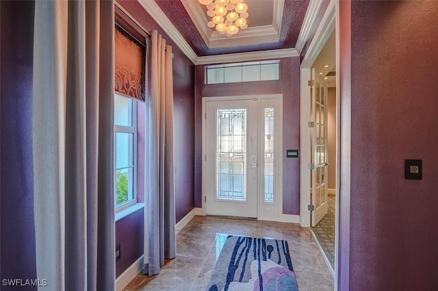 foyer entrance featuring a tray ceiling, plenty of natural light, baseboards, and ornamental molding