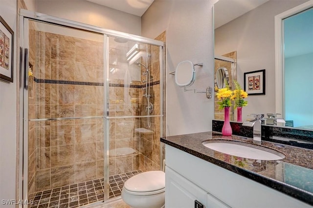 bathroom with vanity, a shower stall, and toilet