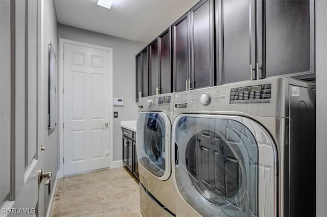 clothes washing area with light tile patterned floors, cabinet space, baseboards, and washing machine and clothes dryer