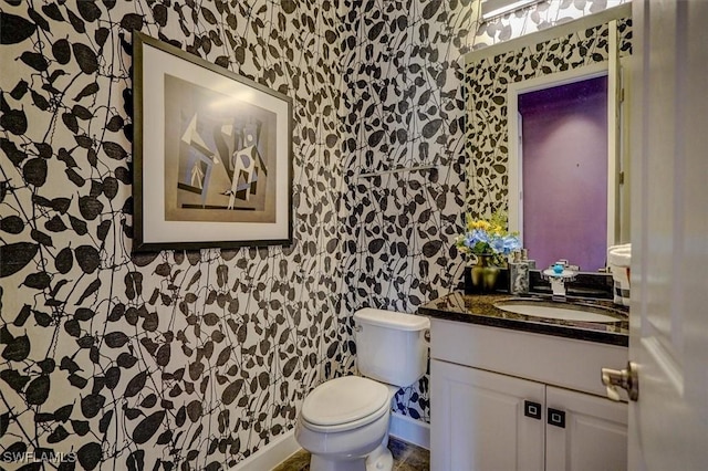 half bathroom with toilet, wallpapered walls, and vanity