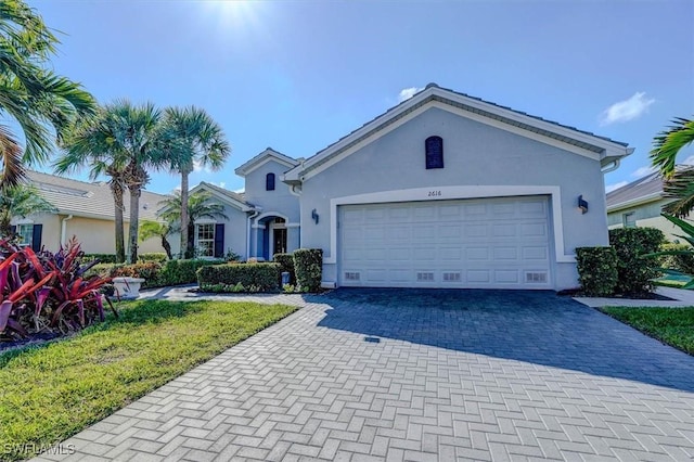 single story home featuring stucco siding, decorative driveway, and a garage