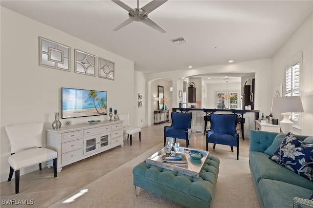 living room with light tile patterned floors and ceiling fan with notable chandelier