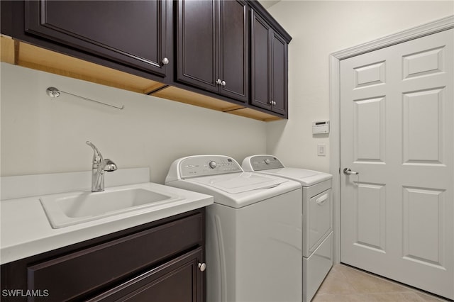 clothes washing area with cabinets, washing machine and dryer, sink, and light tile patterned floors