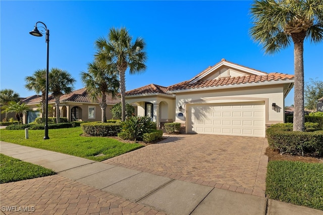 mediterranean / spanish home with a garage and a front lawn