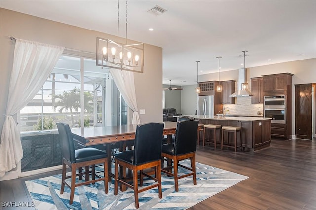 dining area featuring ceiling fan with notable chandelier and dark hardwood / wood-style flooring