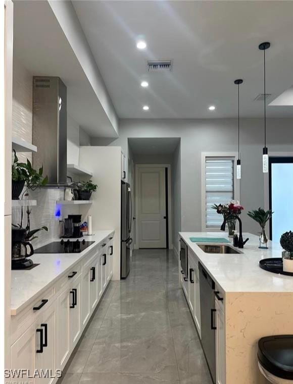 kitchen featuring pendant lighting, sink, white cabinetry, tasteful backsplash, and black appliances