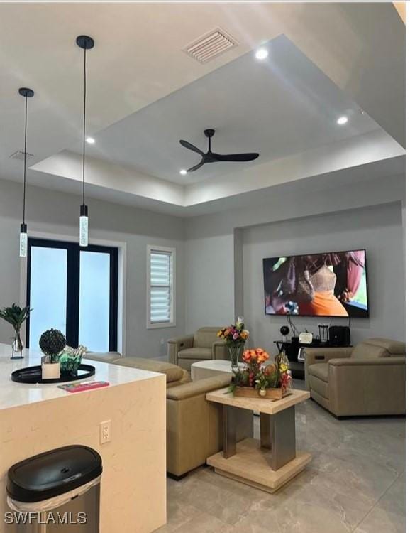 home theater room featuring ceiling fan and a tray ceiling