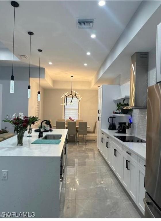 kitchen with white cabinetry, hanging light fixtures, sink, and black electric stovetop