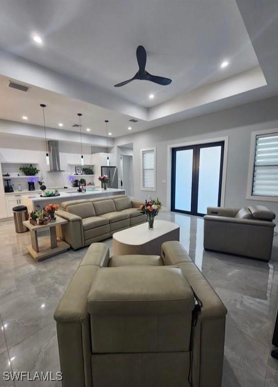 living room with ceiling fan and a tray ceiling