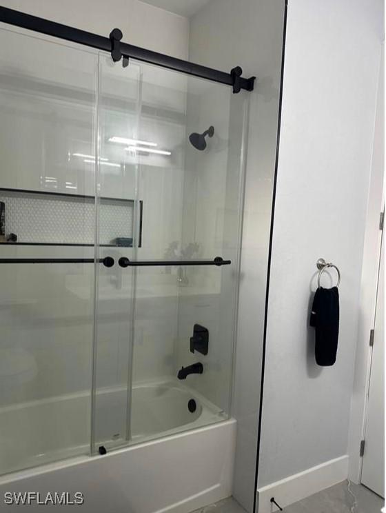 bathroom featuring combined bath / shower with glass door