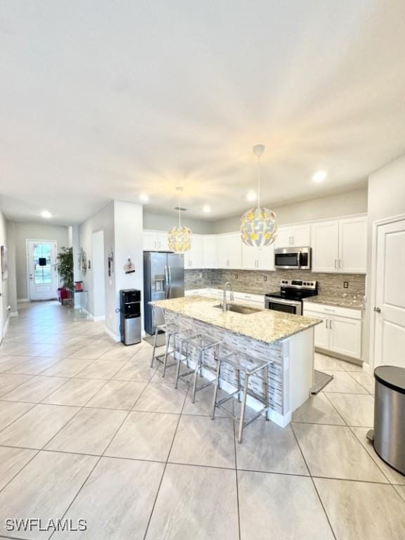 kitchen with pendant lighting, white cabinetry, a breakfast bar area, stainless steel appliances, and a center island with sink